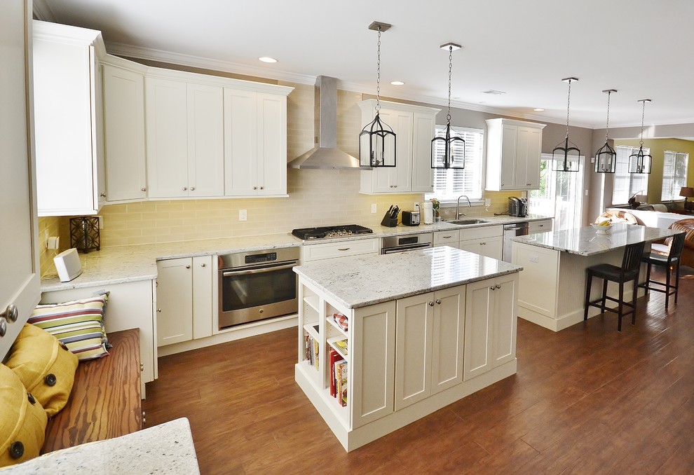 Large transitional galley medium tone wood floor open concept kitchen photo in Philadelphia with an undermount sink, white cabinets, granite countertops, beige backsplash, subway tile backsplash, stainless steel appliances, two islands and shaker cabinets