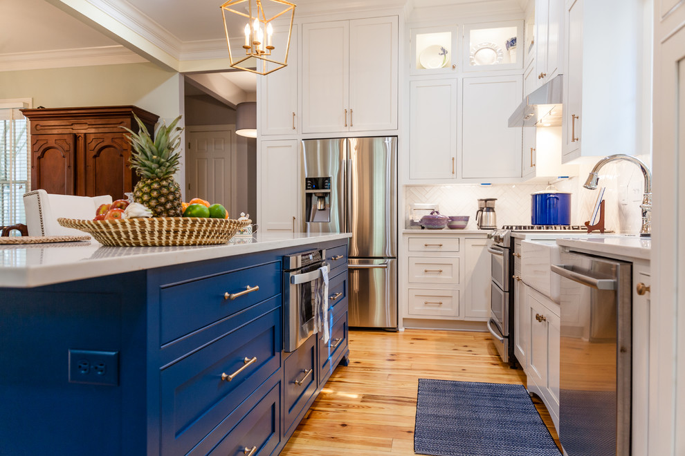 Photo of a large transitional l-shaped open plan kitchen in Charleston with a farmhouse sink, beaded inset cabinets, blue cabinets, quartz benchtops, white splashback, subway tile splashback, stainless steel appliances, medium hardwood floors and with island.