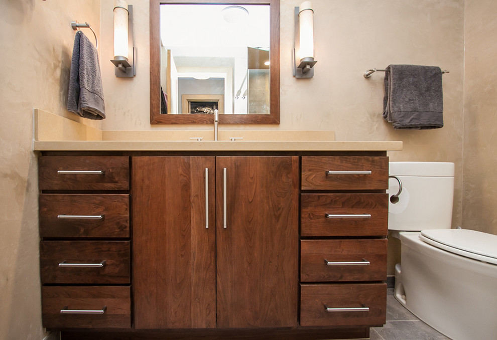 Bathroom - mid-sized transitional 3/4 porcelain tile and gray floor bathroom idea in Phoenix with flat-panel cabinets, medium tone wood cabinets, a two-piece toilet, beige walls, an undermount sink, solid surface countertops and a hinged shower door