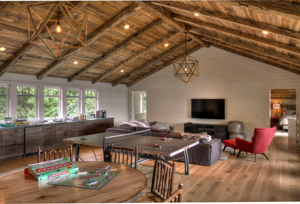 Example of a large mountain style open concept medium tone wood floor game room design in Minneapolis with white walls and a wall-mounted tv