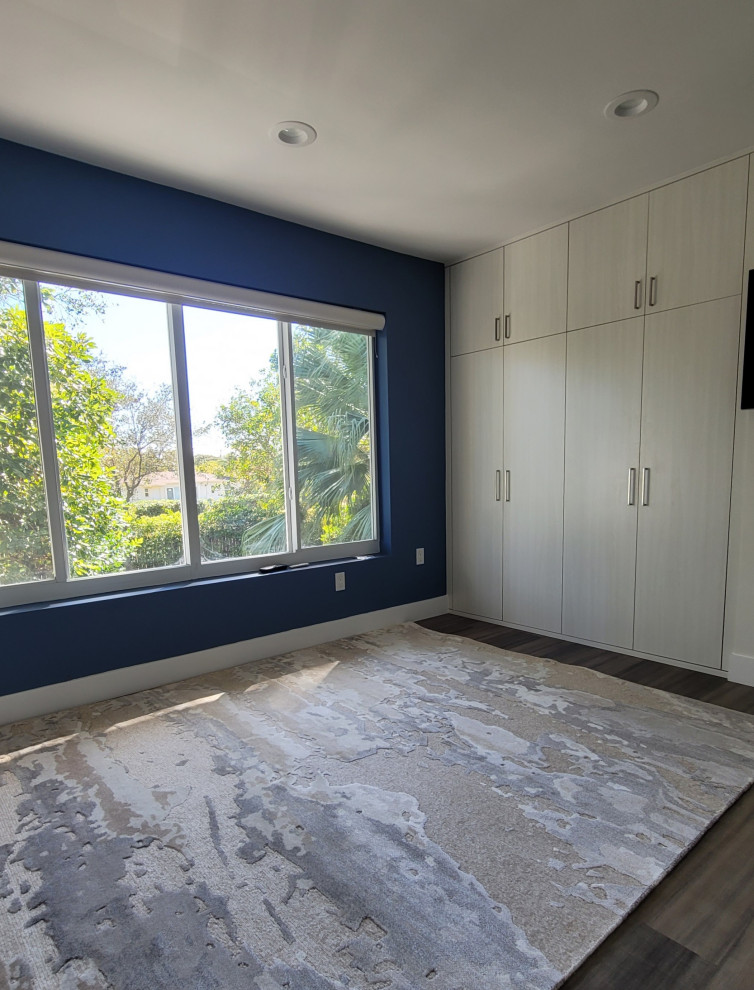 Kleines Modernes Ankleidezimmer mit Einbauschrank, flächenbündigen Schrankfronten, hellen Holzschränken, Vinylboden und braunem Boden in Miami