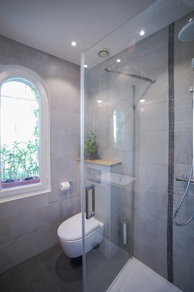 Design ideas for a small contemporary 3/4 bathroom in Paris with beaded inset cabinets, light wood cabinets, a wall-mount toilet, gray tile, porcelain tile, grey walls, porcelain floors, an undermount sink, limestone benchtops, grey floor, a hinged shower door and a corner shower.