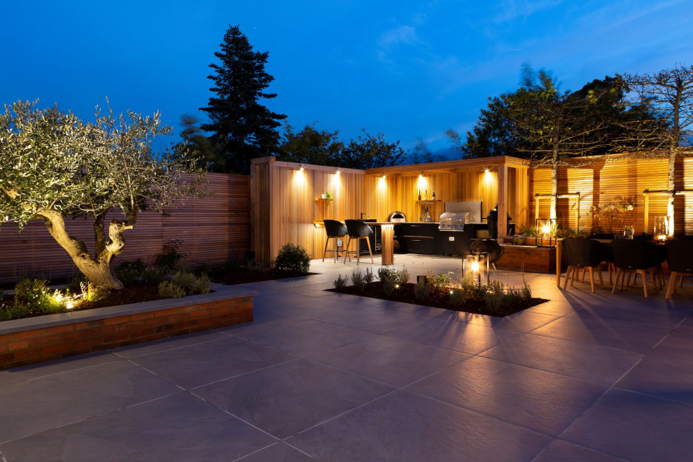 Photo of a mid-sized contemporary backyard patio in Surrey with an outdoor kitchen, natural stone pavers and a pergola.
