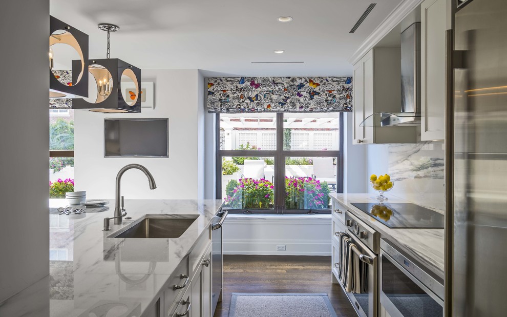 Inspiration for a small transitional galley medium tone wood floor eat-in kitchen remodel in Boston with an undermount sink, recessed-panel cabinets, white cabinets, marble countertops, white backsplash, stone slab backsplash, stainless steel appliances and a peninsula