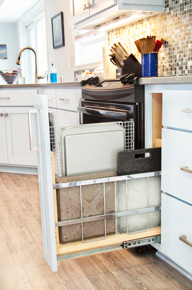 Example of a transitional galley light wood floor enclosed kitchen design in Milwaukee with an undermount sink, shaker cabinets, white cabinets, quartz countertops, multicolored backsplash, glass tile backsplash, black appliances and a peninsula