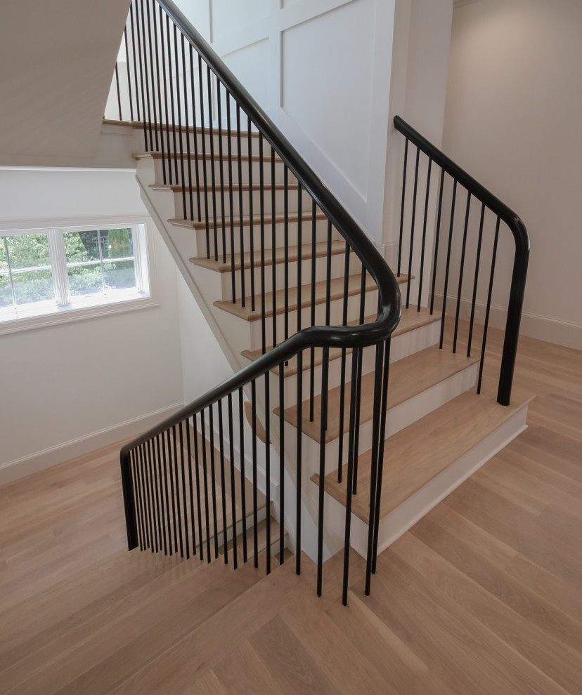 Imagen de escalera en U minimalista grande con escalones de madera, contrahuellas de madera pintada, barandilla de varios materiales y boiserie