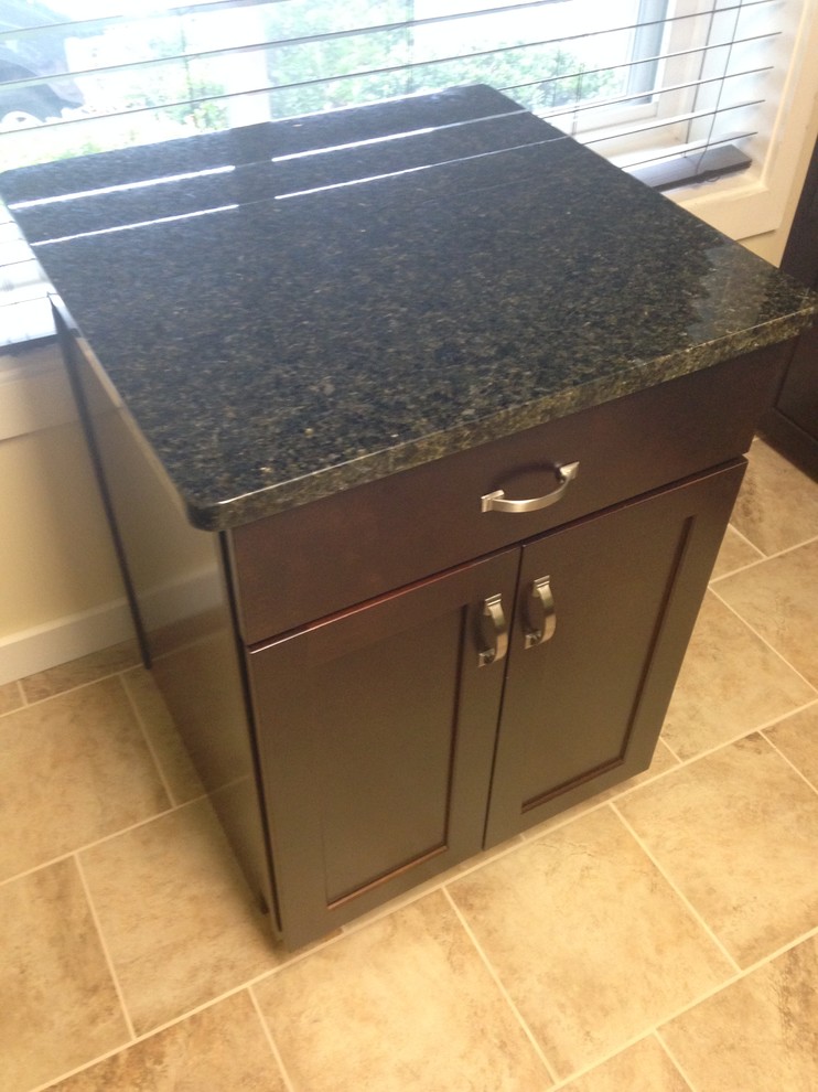 Mid-sized transitional l-shaped porcelain tile enclosed kitchen photo with an undermount sink, shaker cabinets, dark wood cabinets, granite countertops, beige backsplash, stone tile backsplash, stainless steel appliances and an island