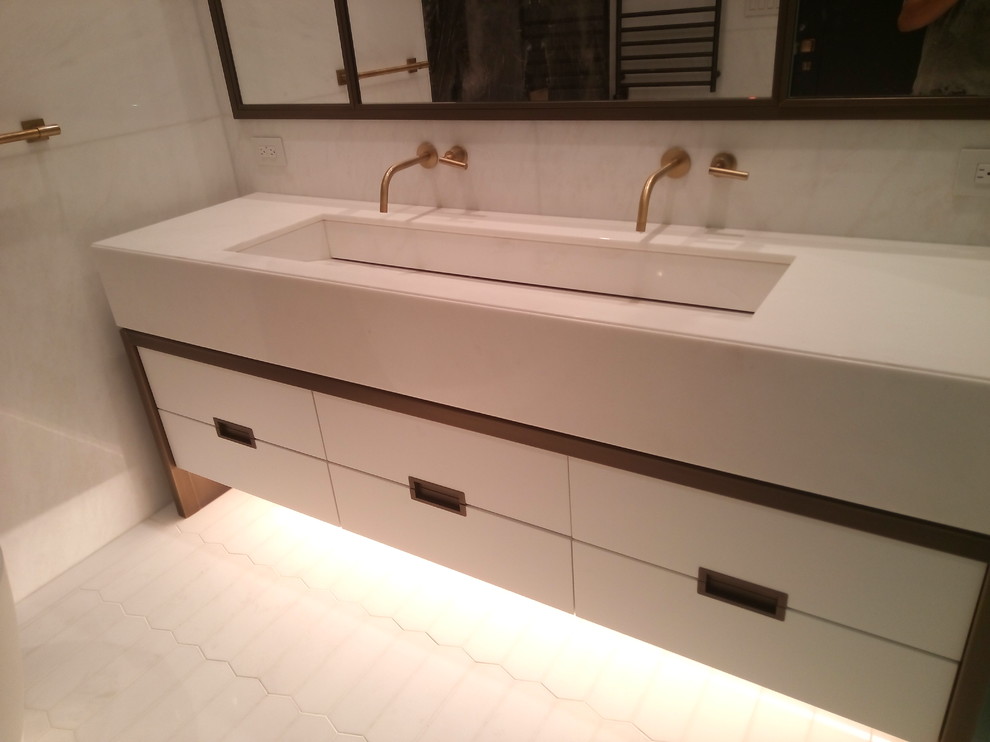 Photo of a large contemporary master bathroom in New York with flat-panel cabinets, white cabinets, a freestanding tub, an alcove shower, an urinal, multi-coloured tile, white tile, stone slab, white walls and a trough sink.
