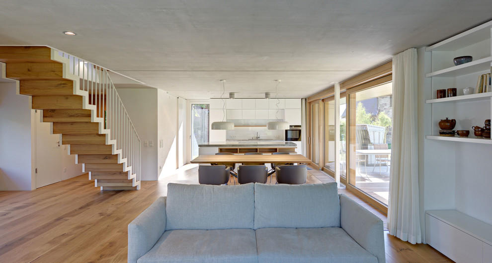 Photo of a contemporary open concept living room in Berlin with white walls and medium hardwood floors.
