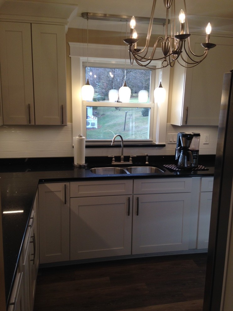 Mid-sized arts and crafts u-shaped vinyl floor home design photo with a double-bowl sink, shaker cabinets, white cabinets, quartz countertops, white backsplash, porcelain backsplash, stainless steel appliances and no island
