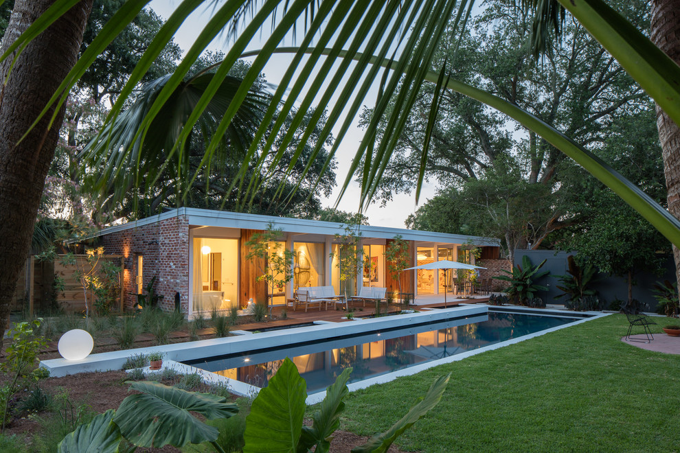 Photo of a midcentury backyard rectangular pool in New Orleans with natural stone pavers.