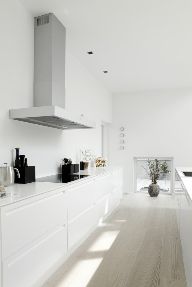 Scandinavian galley kitchen in West Midlands with flat-panel cabinets, white cabinets, light hardwood floors, with island and white floor.