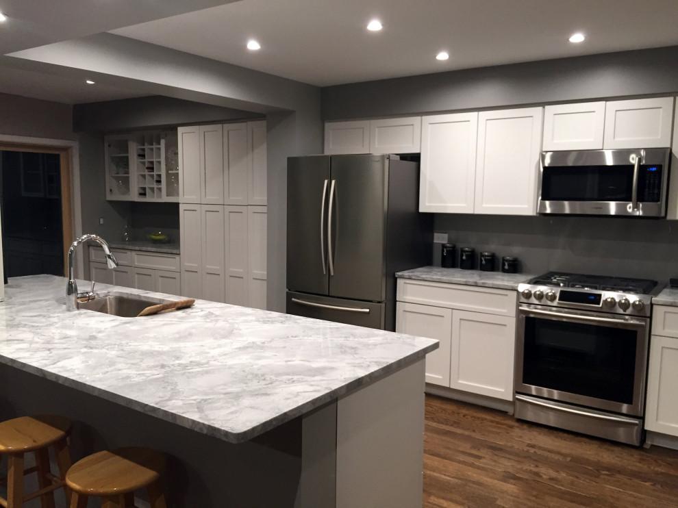 Photo of an expansive contemporary galley kitchen in Chicago with shaker cabinets, white cabinets, marble benchtops and with island.