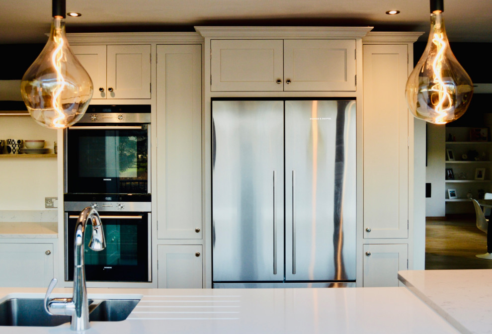 Bild på ett stort vintage vit vitt kök och matrum, med en integrerad diskho, skåp i shakerstil, grå skåp, bänkskiva i kvartsit, vitt stänkskydd, rostfria vitvaror, klinkergolv i keramik, en köksö och grått golv