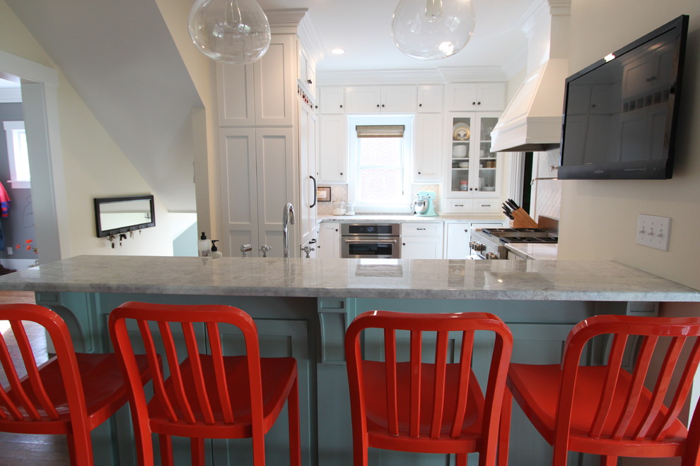 Inspiration for a mid-sized transitional medium tone wood floor eat-in kitchen remodel in Omaha with a farmhouse sink, shaker cabinets, white cabinets, quartzite countertops, white backsplash, ceramic backsplash, paneled appliances and a peninsula