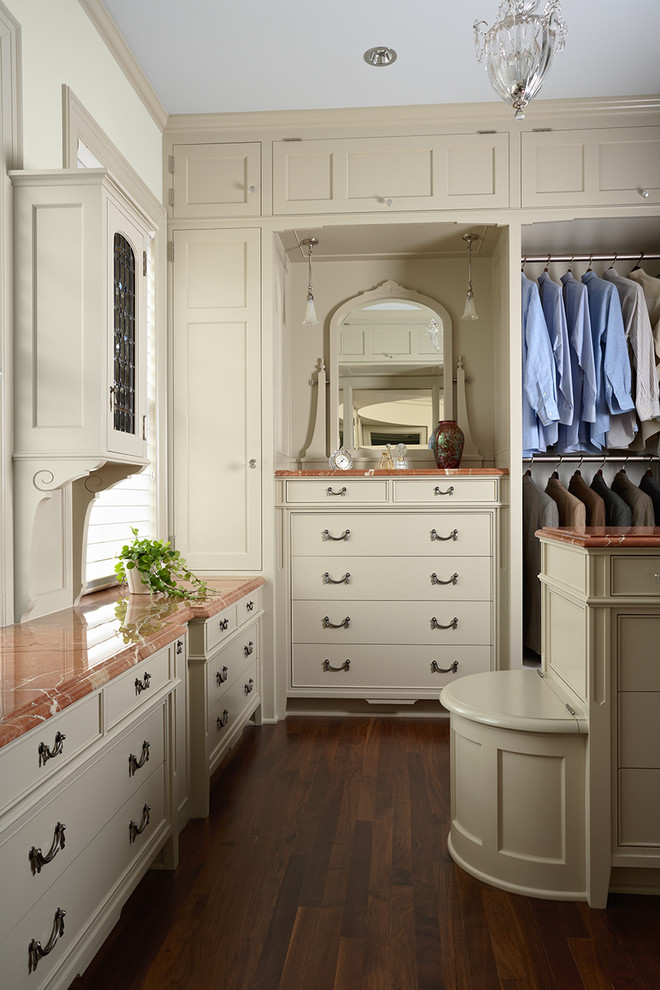 Photo of a traditional gender-neutral dressing room in Minneapolis with beige cabinets and dark hardwood floors.
