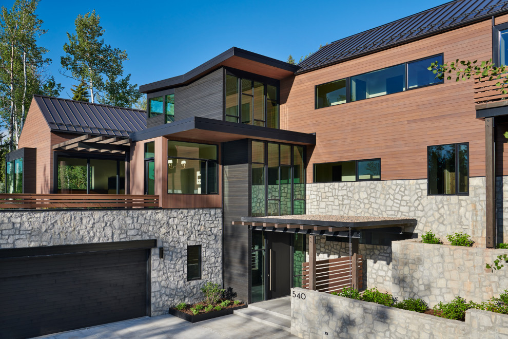 Expansive contemporary three-storey multi-coloured house exterior in Denver with a metal roof, mixed siding and a hip roof.
