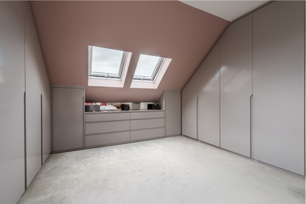 Cette photo montre une grande armoire encastrée moderne avec un placard à porte plane, des portes de placard grises, moquette, un sol gris et un plafond décaissé.