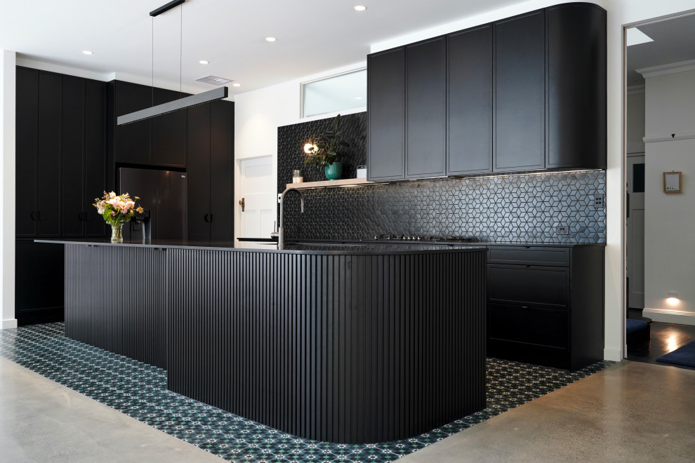 This is an example of a large contemporary l-shaped open plan kitchen in Sydney with a submerged sink, shaker cabinets, black cabinets, engineered stone countertops, black splashback, mosaic tiled splashback, black appliances, ceramic flooring, an island, green floors and black worktops.
