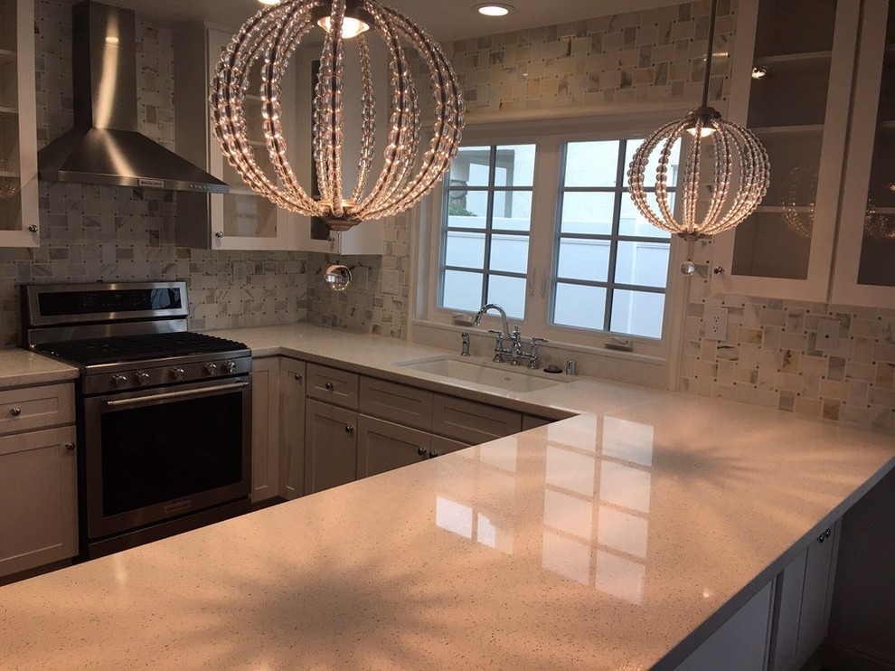 Mid-sized transitional u-shaped medium tone wood floor and brown floor open concept kitchen photo in Los Angeles with an undermount sink, recessed-panel cabinets, white cabinets, quartz countertops, white backsplash, ceramic backsplash, stainless steel appliances, a peninsula and white countertops