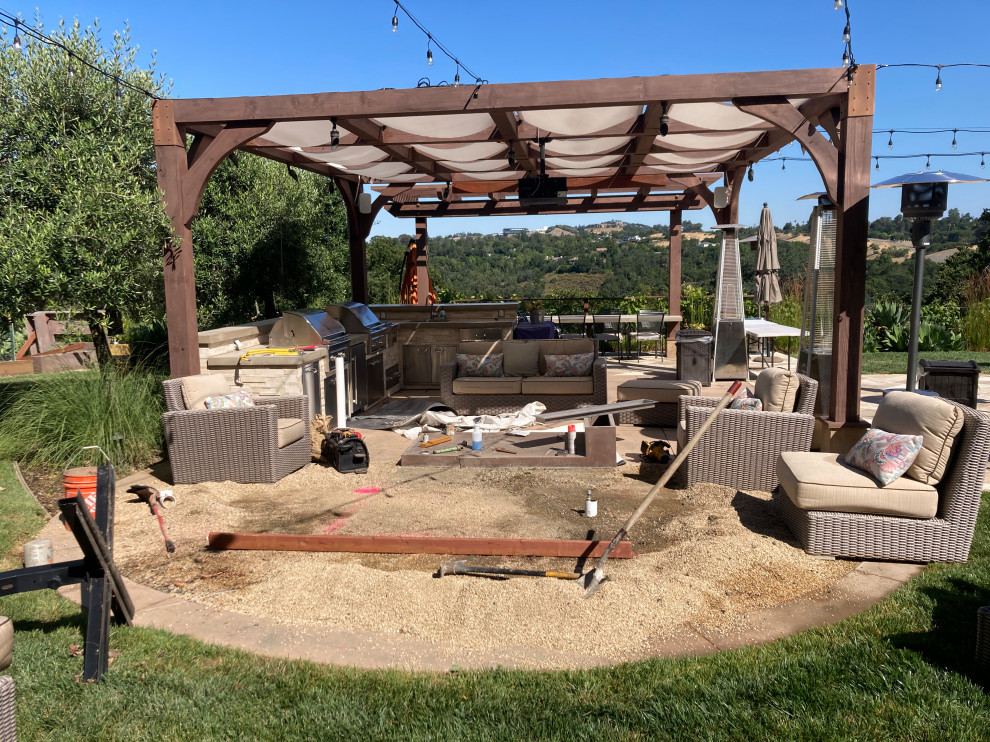 This is an example of an expansive country backyard patio in San Francisco with an outdoor kitchen, natural stone pavers and a pergola.