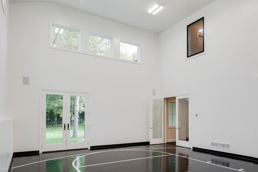 Expansive transitional indoor sport court in Minneapolis with white walls and black floor.