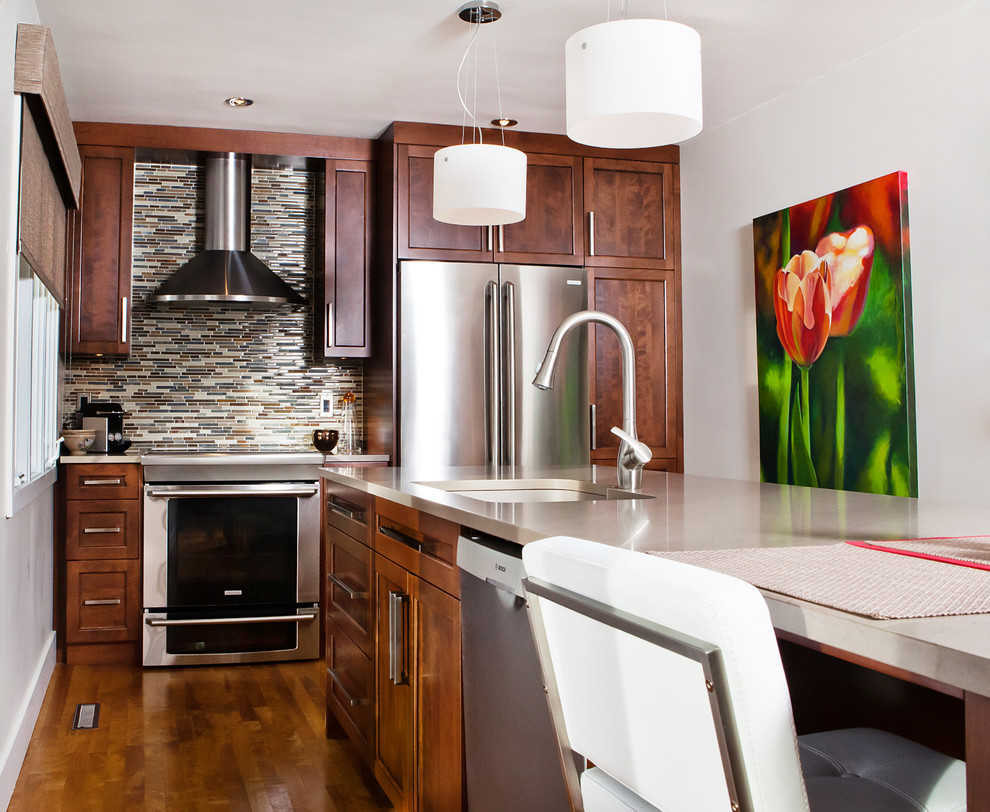 Contemporary eat-in kitchen in Montreal with an undermount sink, shaker cabinets, brown cabinets, quartzite benchtops, multi-coloured splashback, glass tile splashback and stainless steel appliances.