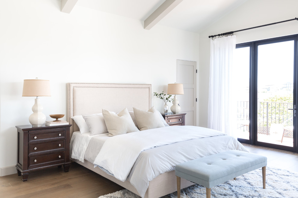 Inspiration for a mediterranean bedroom in Los Angeles with white walls, medium hardwood floors and brown floor.