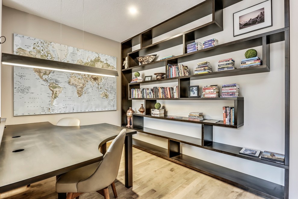 This is an example of a mid-sized transitional study room in Calgary with grey walls, medium hardwood floors, a built-in desk and brown floor.