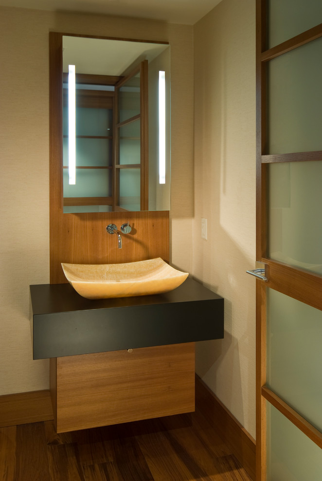 Inspiration for a mid-sized asian powder room in San Francisco with flat-panel cabinets, medium wood cabinets, a vessel sink, beige walls, medium hardwood floors and brown floor.