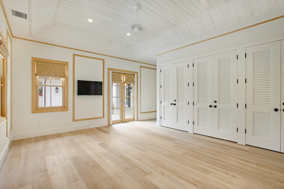 This is an example of a mid-sized beach style master bedroom in Miami with white walls and light hardwood floors.