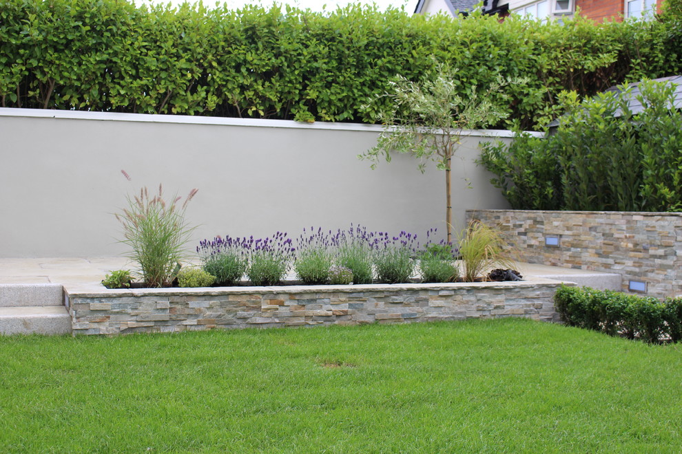 This is an example of a mid-sized traditional backyard partial sun garden in Dublin with natural stone pavers.