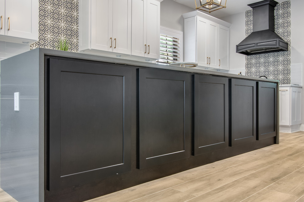 Inspiration for a large transitional l-shaped porcelain tile and gray floor kitchen pantry remodel in Houston with a farmhouse sink, shaker cabinets, white cabinets, quartzite countertops, white backsplash, glass tile backsplash, stainless steel appliances, an island and white countertops