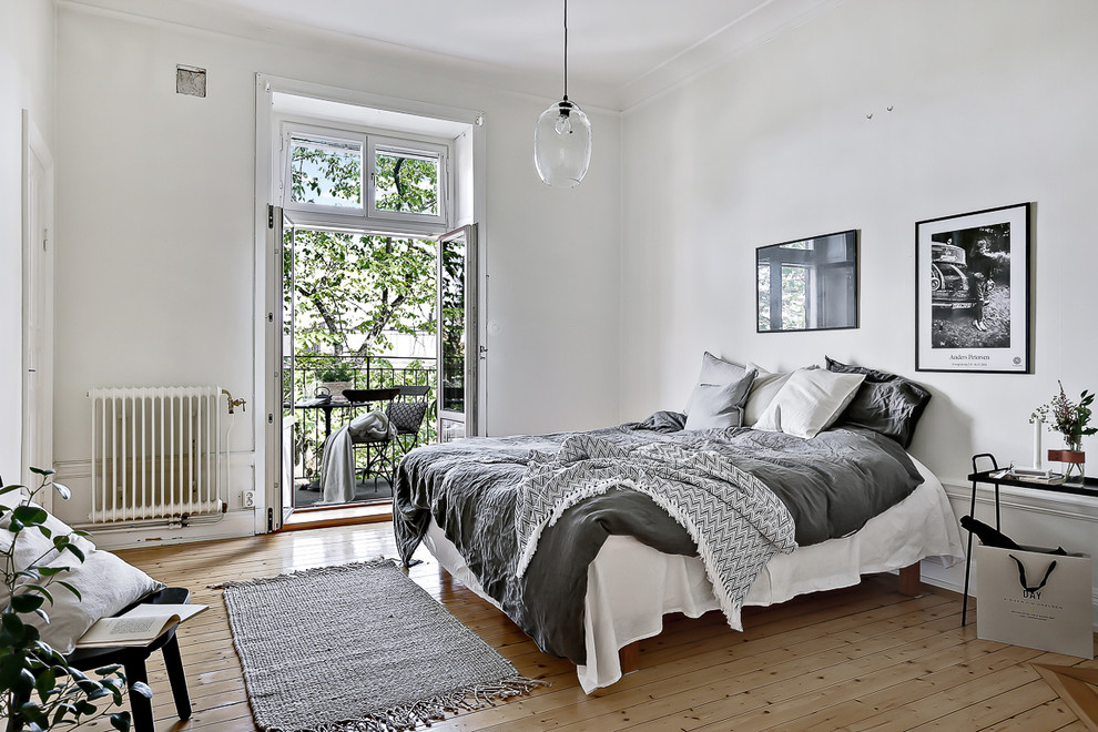 Photo of a mid-sized scandinavian master bedroom in Stockholm with white walls and light hardwood floors.