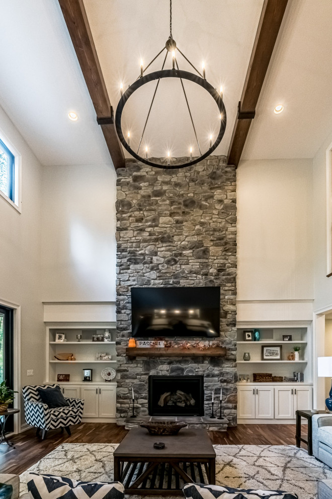 Inspiration for a large arts and crafts open concept family room in Other with a game room, grey walls, medium hardwood floors, a standard fireplace, a stone fireplace surround, a built-in media wall, brown floor and exposed beam.