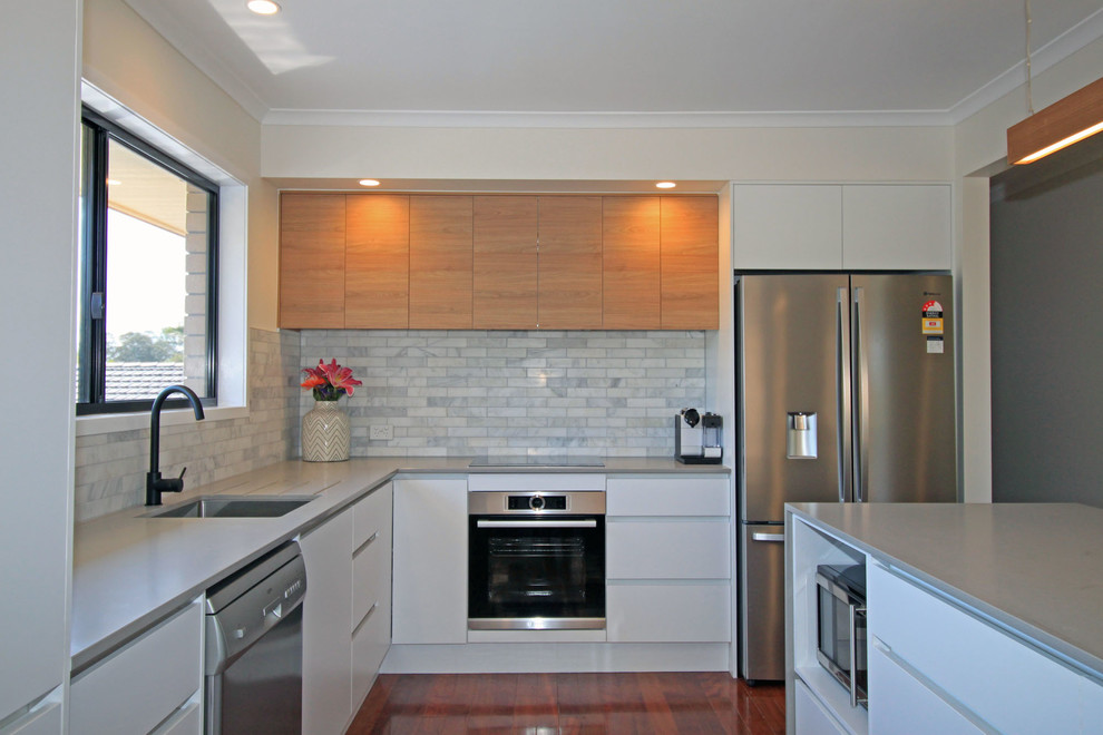 Inspiration for a mid-sized modern l-shaped open plan kitchen in Brisbane with an undermount sink, flat-panel cabinets, white cabinets, quartz benchtops, grey splashback, marble splashback, stainless steel appliances, dark hardwood floors, with island, brown floor and grey benchtop.
