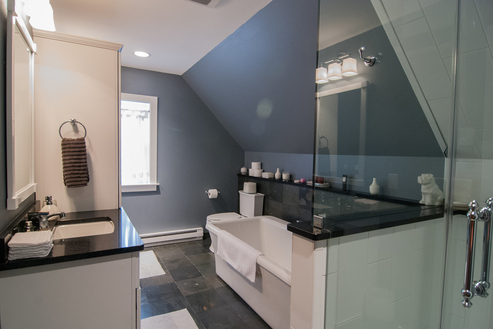 This is an example of a mid-sized contemporary master bathroom in Milwaukee with recessed-panel cabinets, white cabinets, a freestanding tub, a corner shower, white tile, ceramic tile, grey walls, slate floors, an undermount sink and engineered quartz benchtops.