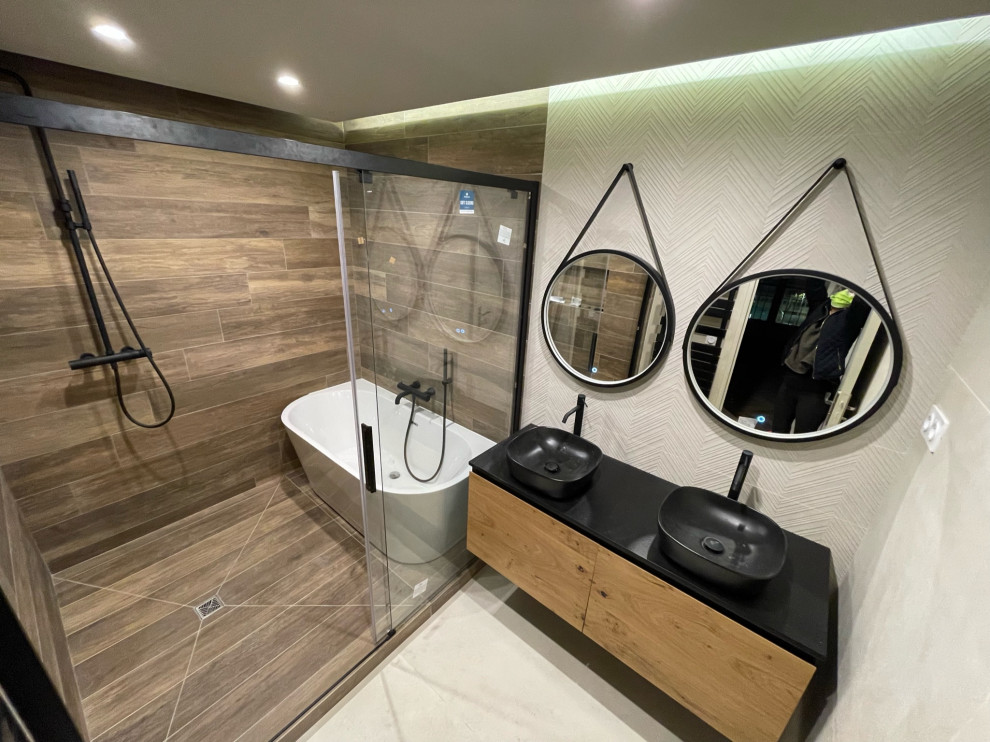 Inspiration for a mid-sized contemporary master wet room bathroom in Other with black cabinets, a freestanding tub, beige tile, wood-look tile, beige walls, wood-look tile, a drop-in sink, tile benchtops, a sliding shower screen, black benchtops, a double vanity, a floating vanity and recessed.