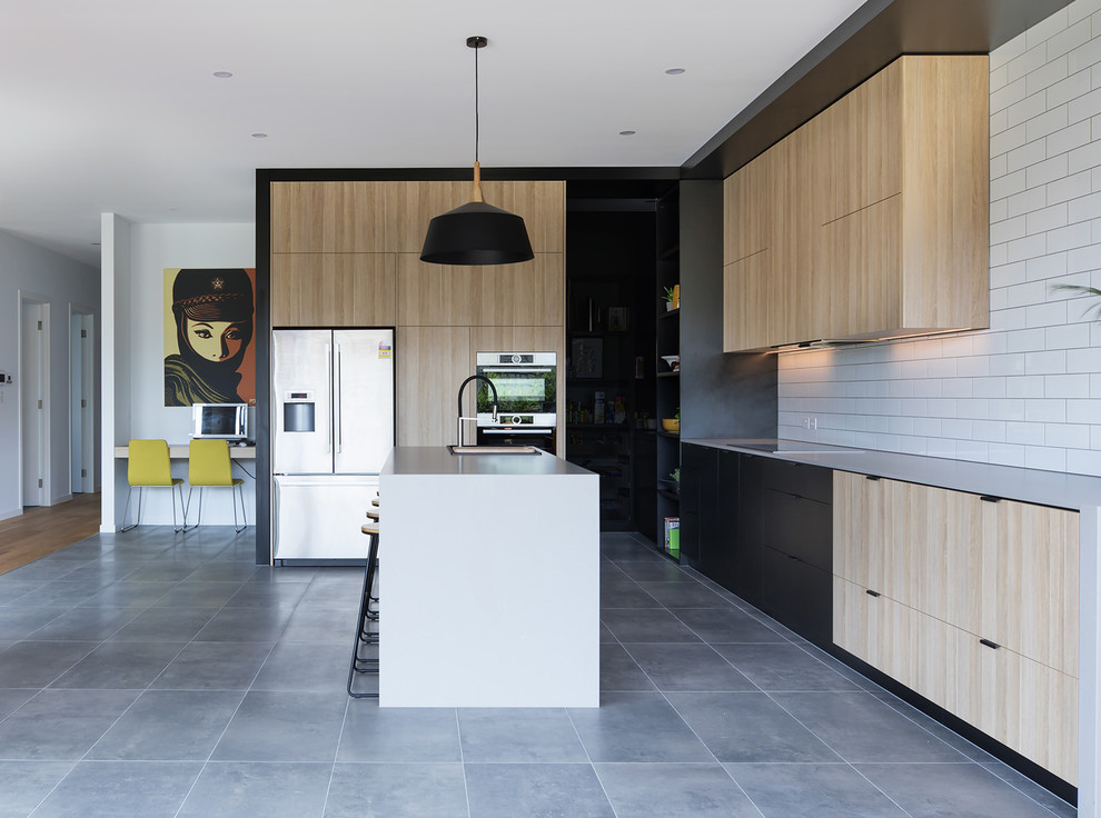 Mid-sized contemporary l-shaped kitchen pantry in Adelaide with a double-bowl sink, flat-panel cabinets, light wood cabinets, quartz benchtops, white splashback, subway tile splashback, stainless steel appliances, with island and grey floor.