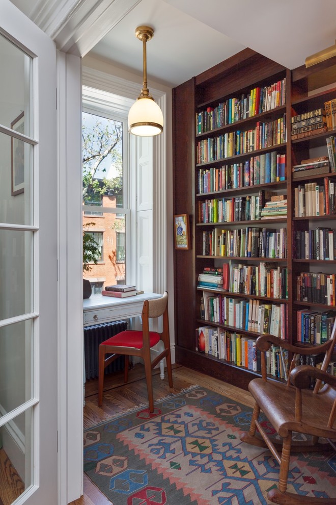 Inspiration for a small transitional home office in New York with a library, medium hardwood floors and a freestanding desk.