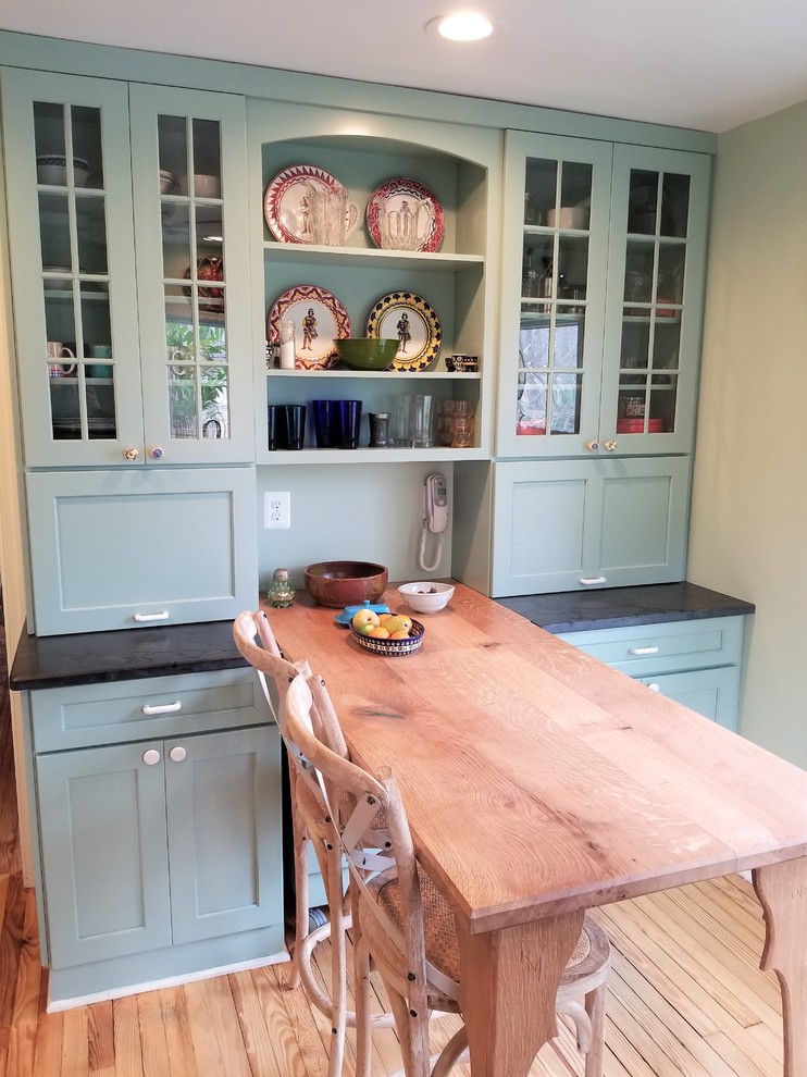 Example of a small eclectic u-shaped light wood floor and brown floor enclosed kitchen design in DC Metro with a farmhouse sink, shaker cabinets, blue cabinets, soapstone countertops, white backsplash, subway tile backsplash, stainless steel appliances and no island