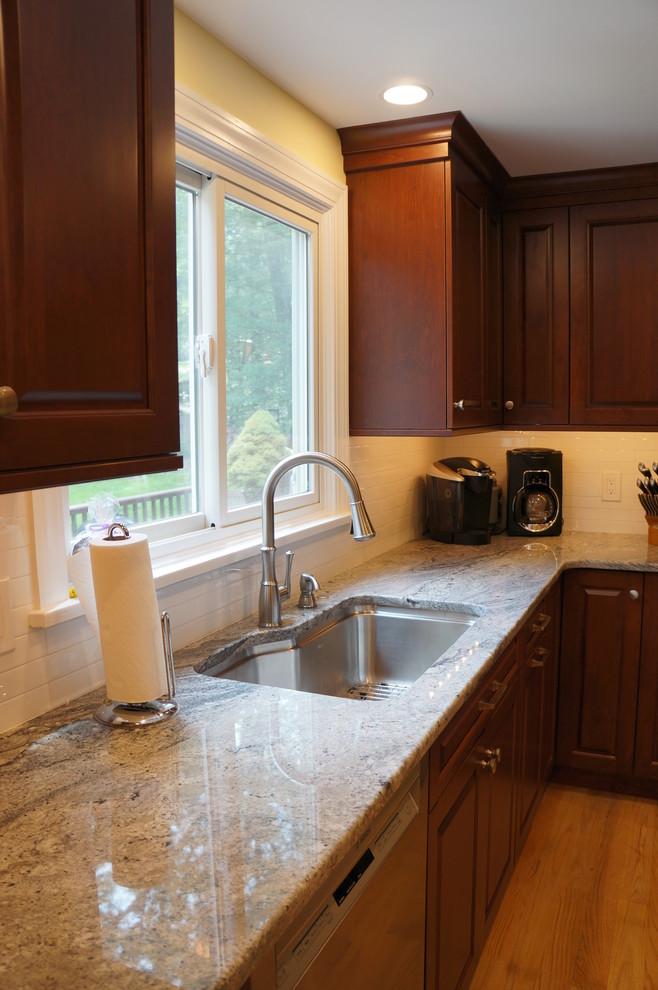 Mid-sized transitional galley light wood floor eat-in kitchen photo in Boston with an undermount sink, raised-panel cabinets, dark wood cabinets, quartz countertops, white backsplash, ceramic backsplash, stainless steel appliances and an island