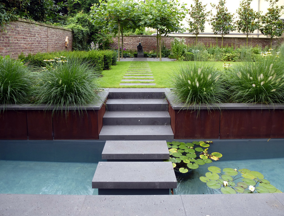 Mid-sized contemporary side yard full sun formal garden in Cologne with concrete pavers for summer.