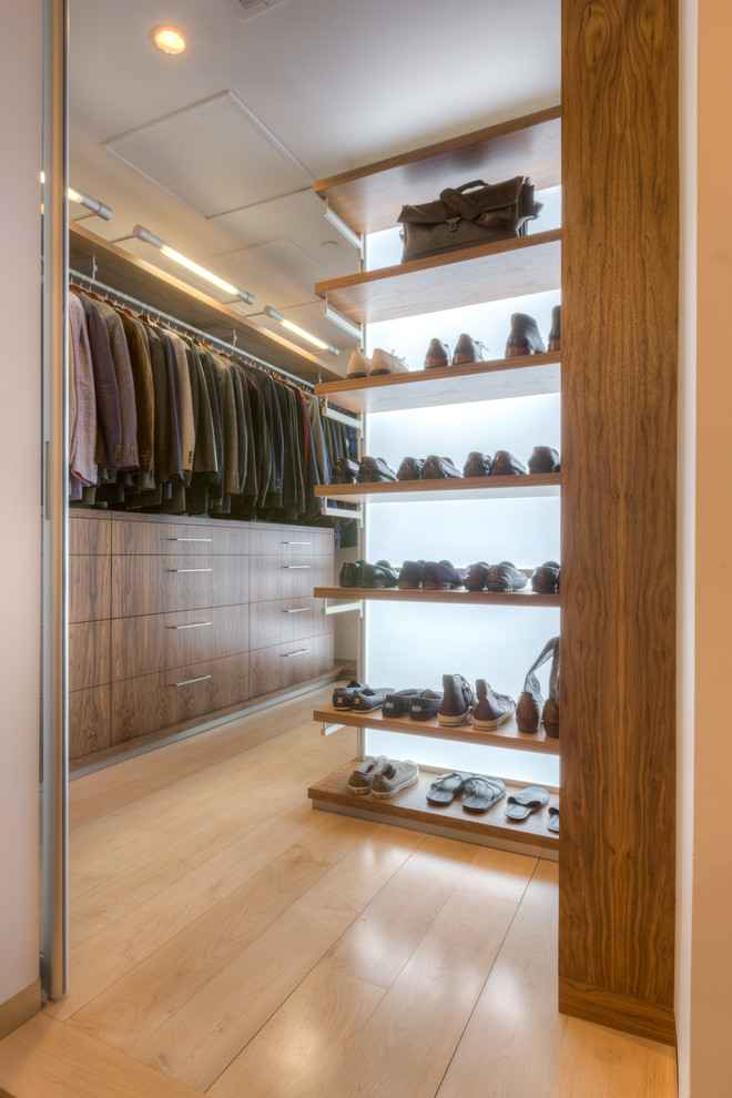 Photo of an expansive modern gender-neutral walk-in wardrobe in Kansas City with flat-panel cabinets, medium wood cabinets and light hardwood floors.