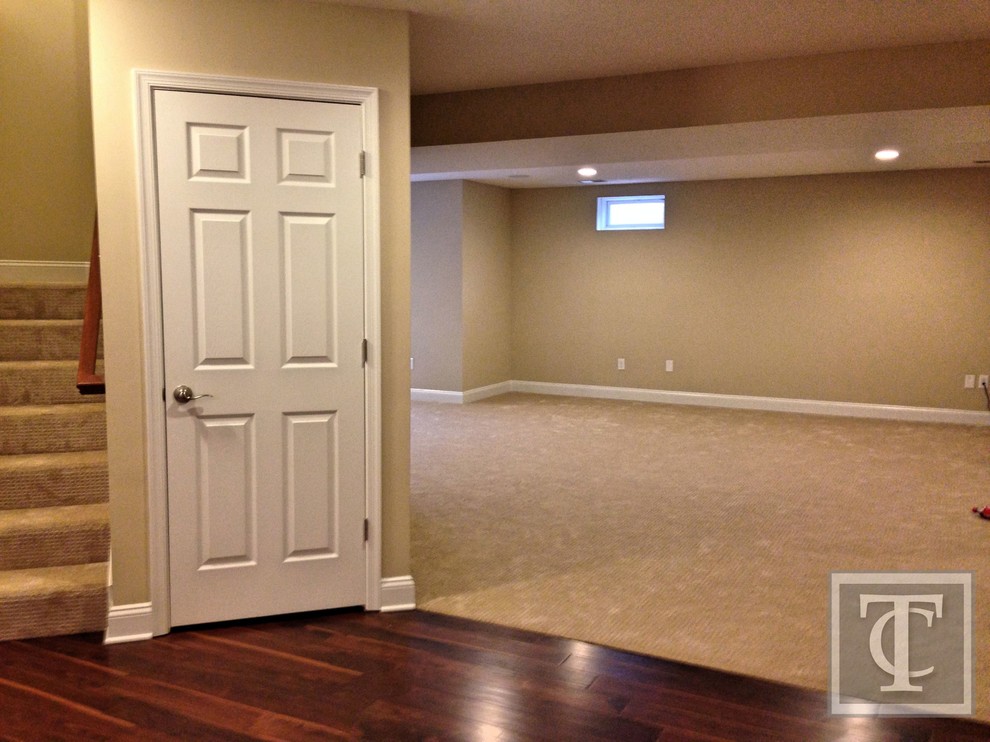 This is an example of a large contemporary walk-out basement in Baltimore with beige walls and carpet.