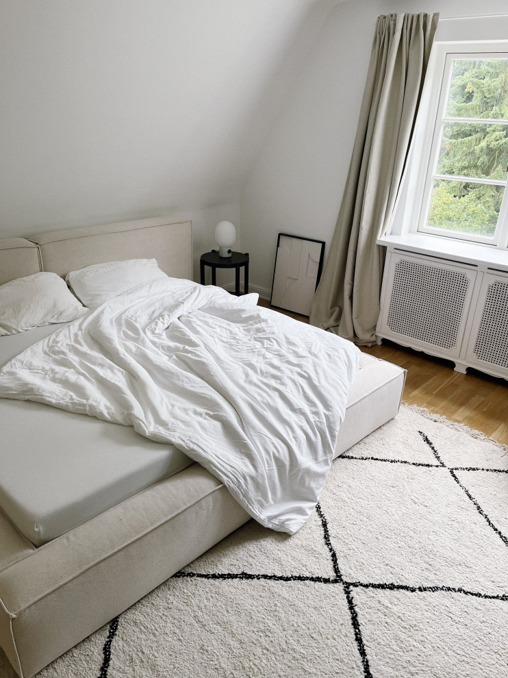 Imagen de dormitorio principal y gris y blanco contemporáneo grande con paredes blancas y suelo de madera en tonos medios