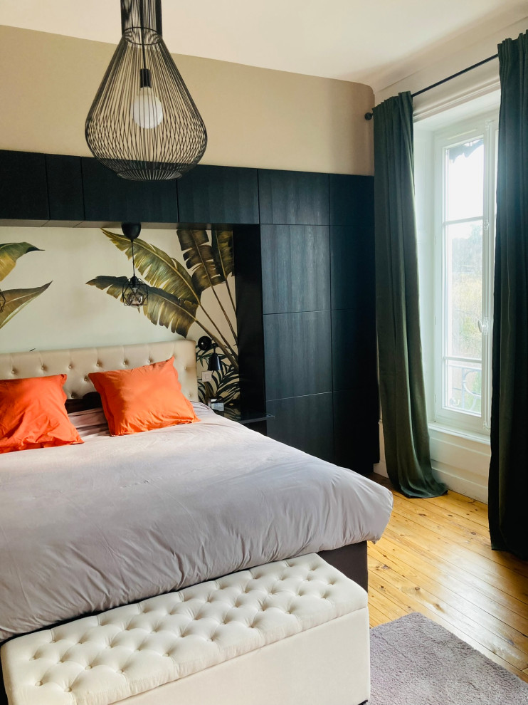 Modelo de dormitorio principal y beige y blanco tropical grande sin chimenea con paredes beige, suelo de madera clara y papel pintado