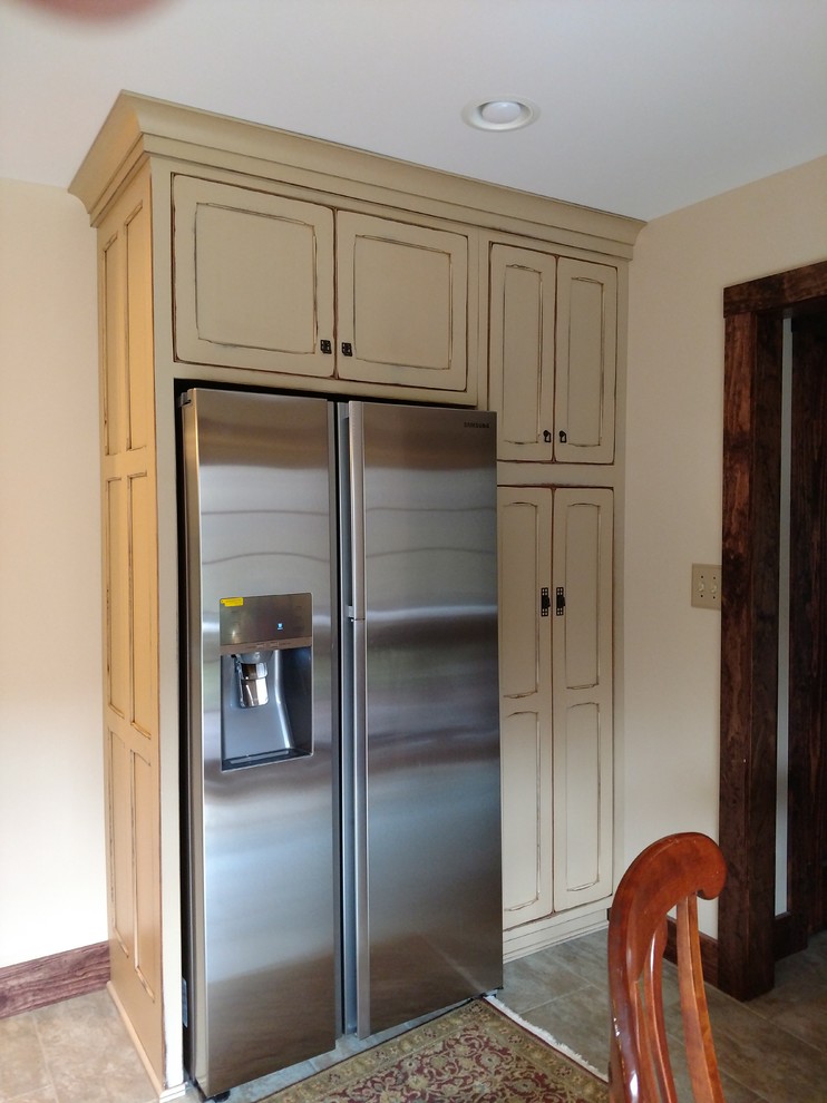 Example of a small mountain style kitchen design with a single-bowl sink, recessed-panel cabinets, distressed cabinets, granite countertops, multicolored backsplash, ceramic backsplash, stainless steel appliances and an island