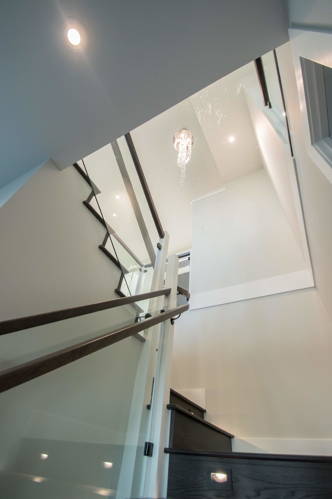 This is an example of a large traditional wood u-shaped staircase in Vancouver with wood risers and glass railing.