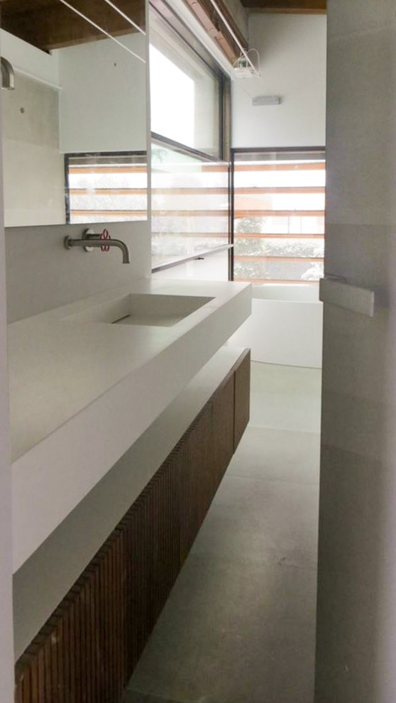 Mid-sized modern master bathroom in Detroit with a wall-mount sink, furniture-like cabinets, medium wood cabinets, engineered quartz benchtops, a freestanding tub, an open shower, a wall-mount toilet, gray tile, cement tile, grey walls and ceramic floors.